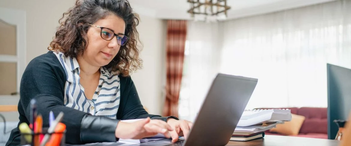 Woman with checkered scarf working at laptop in a well lit room