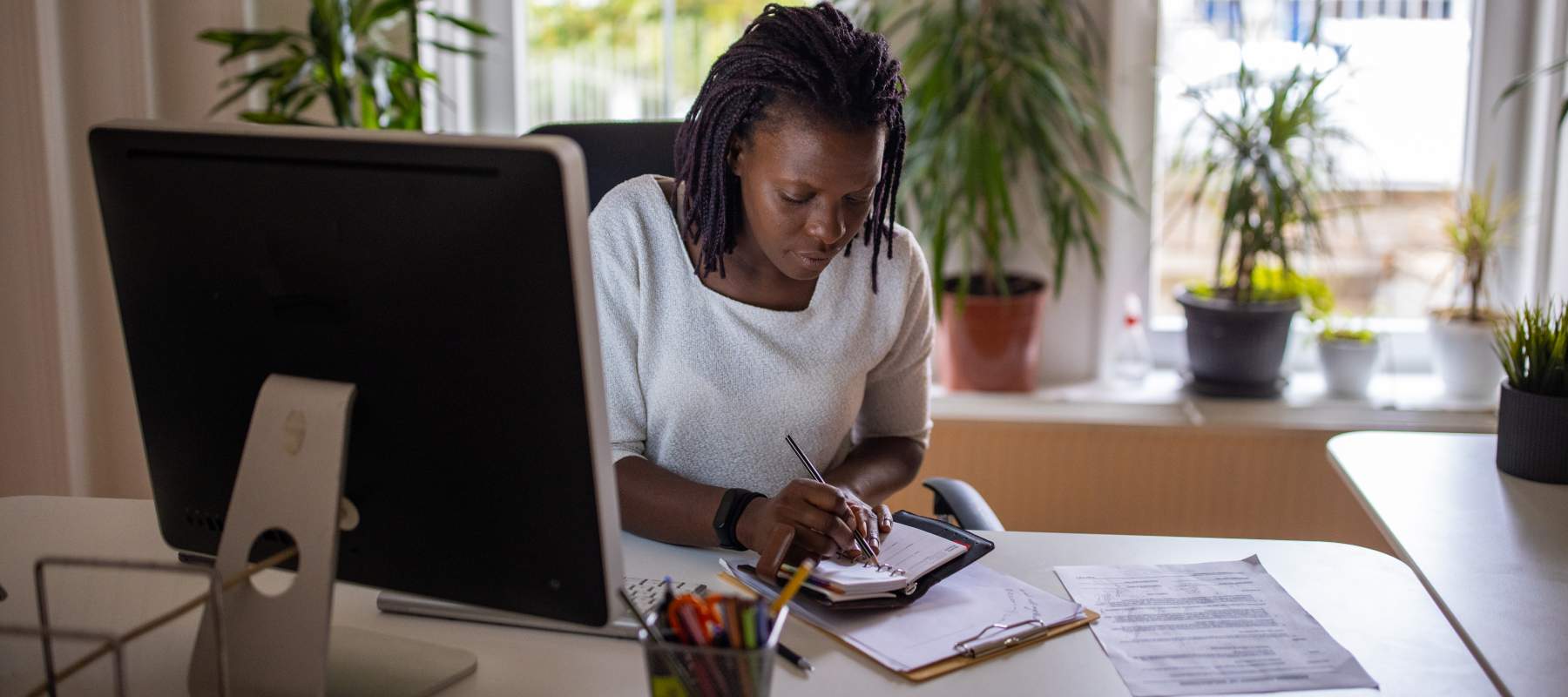 A remote executive assistant in her office, writing in her planner.