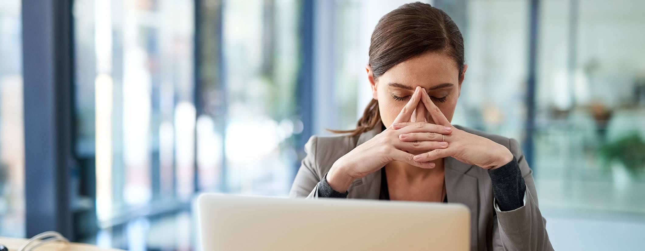 Woman frustrated at computer desk with her head in her hands.