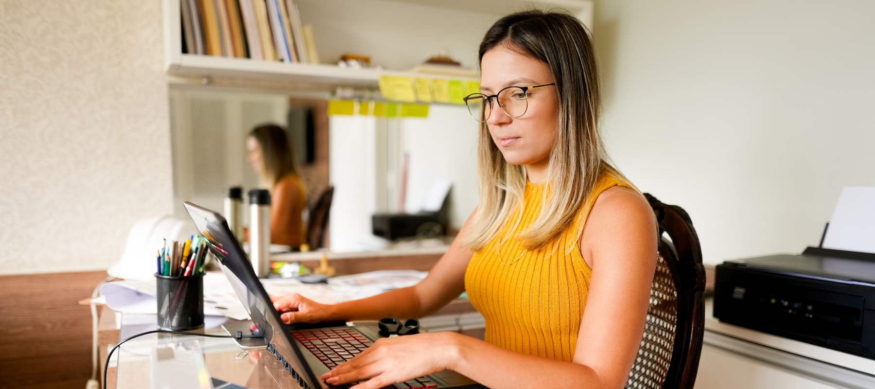 Woman executive assistant sitting at laptop in home, typing while working.