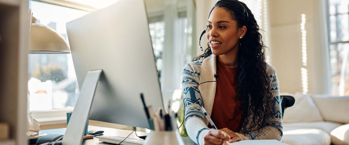 Woman sitting at a desk with a headset on, looking at computer screen