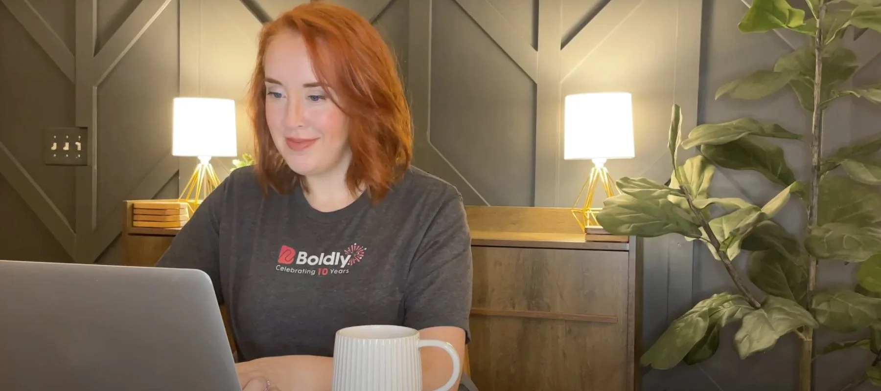 Woman with Boldly shirt on sitting at a computer and working