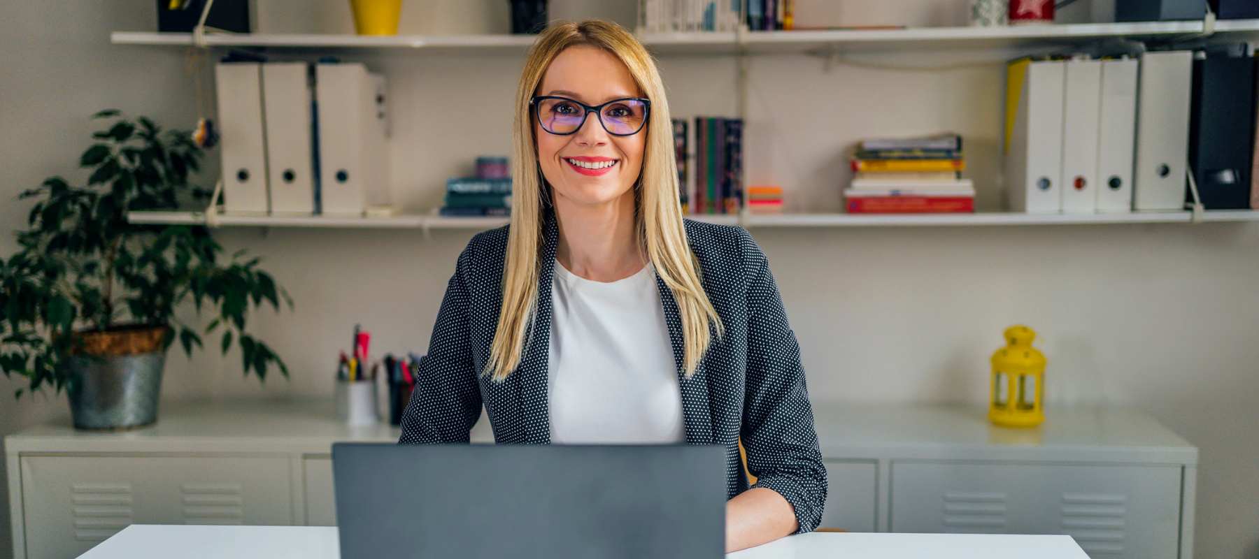 A professional executive assistant working on a laptop, managing schedules and calendars using AI tools in a modern office setting.