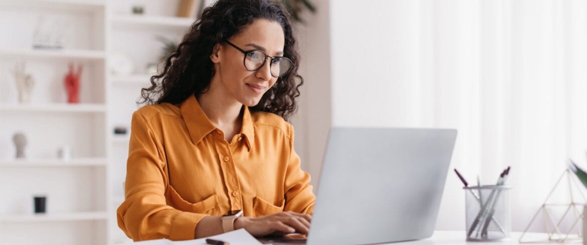 Photo of an executive assistant using AI tools on a laptop while applying human judgment and professional expertise to her work.