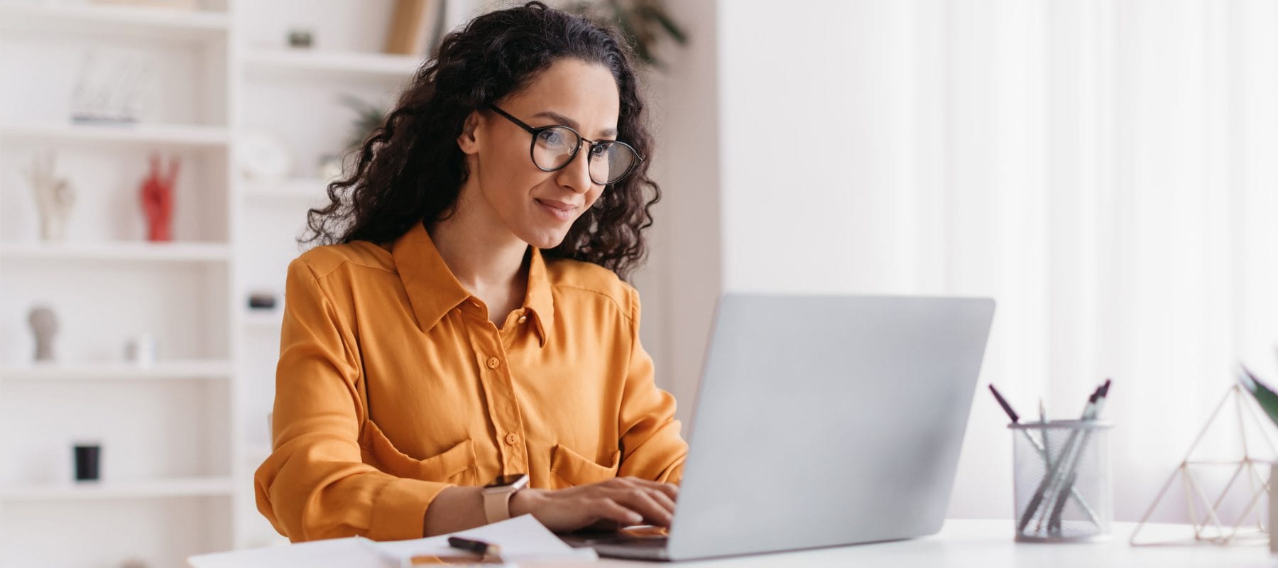 Photo of an executive assistant using AI tools on a laptop while applying human judgment and professional expertise to her work.